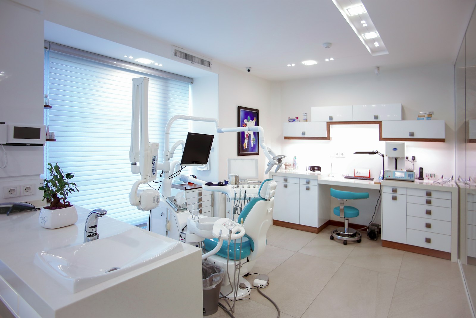 Modern treatment room with teal chairs and a staff workstation